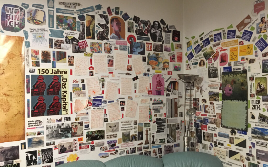 Eine weiße Wand voll beklebt mit lauter Zeitungsausschnitten und sonstigen Schnipseln